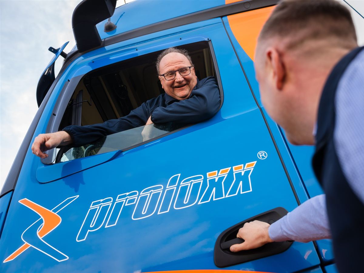 Fahrer von proloxx lehnt lachend aus dem Fenster seines Lkw